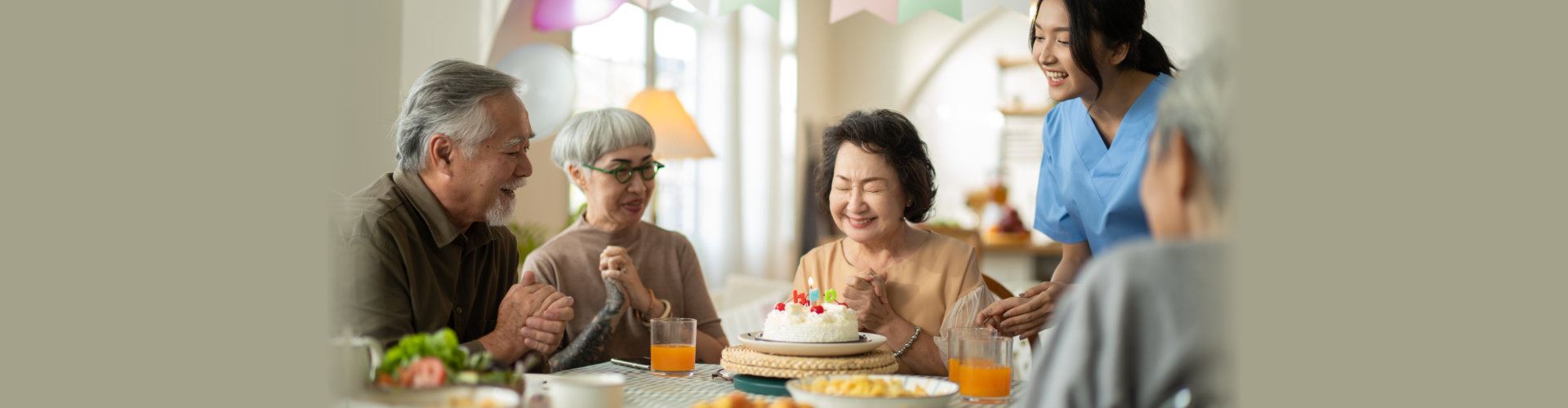 Group of asian senior people having birthday party in a nursing home, celebrating birthday at retirement home with friends.nurse giving birthday cake to happy grandma,who then blowing out candles